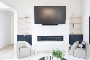 Custom built-in entertainment center with TV above fireplace and shelving by Carlyle Cabinets
